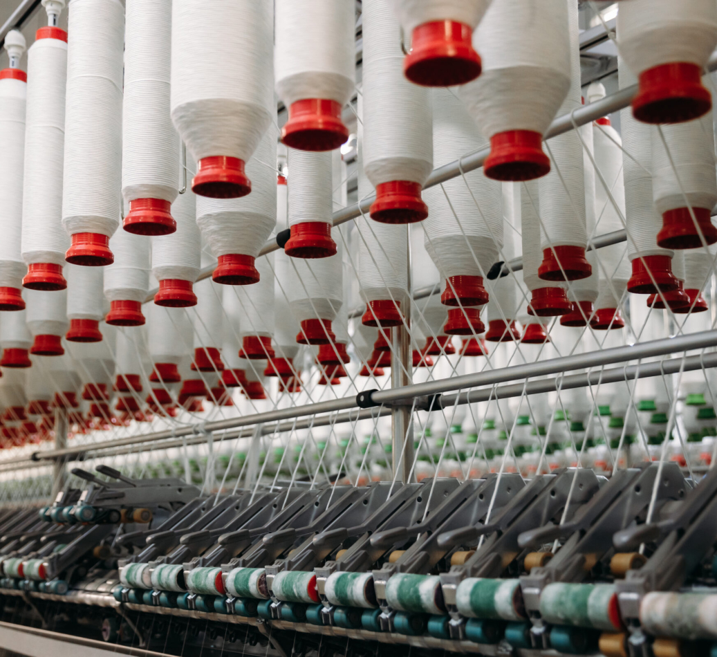 White rolls of industrial cotton thread for textile garment production on a machine.